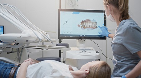 a dental assistant showing a patient her digital scans on a chairside monitor