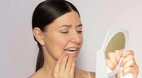 Concerned woman examining her gums in mirror