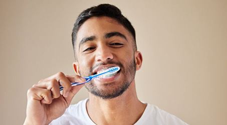Man brushing his teeth while smiling