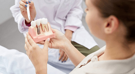 a patient holding a model of a dental implant