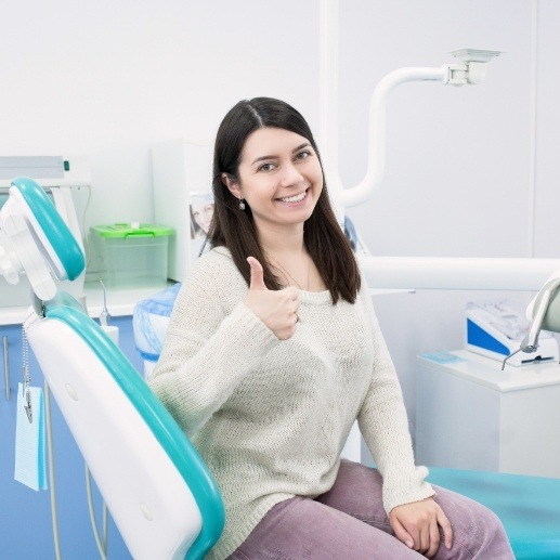 Woman in dental chair giving a thumbs up