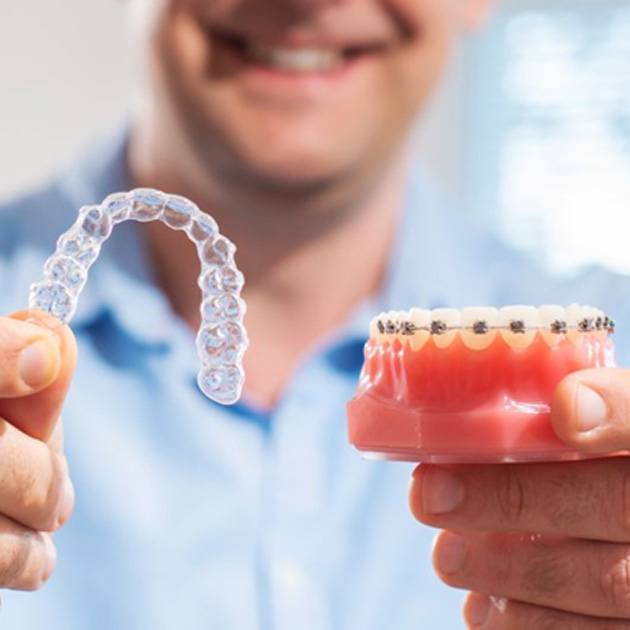 a dentist placing Invisalign aligners on model teeth