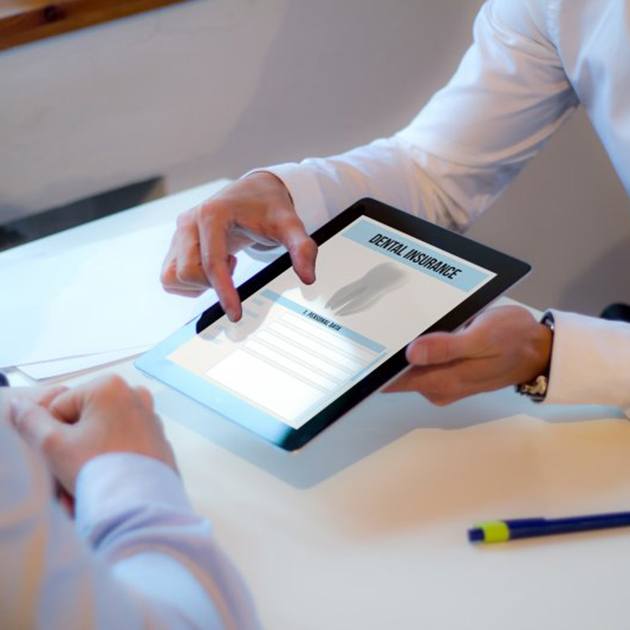 Dentist and patient reviewing a dental insurance plan on a tablet