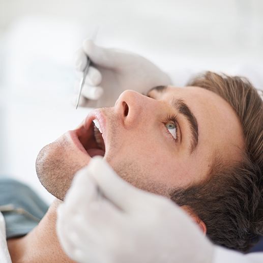 Patient looking up at dentist approaching to examine his mouth