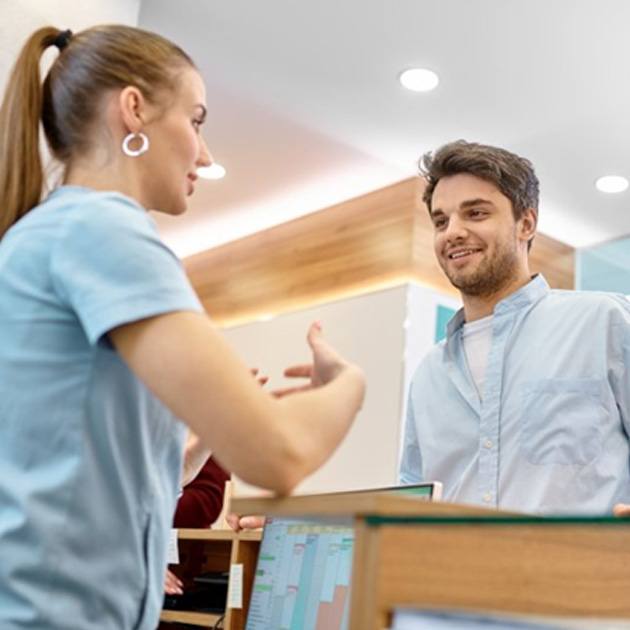 a patient speaking to front desk about dental insurance