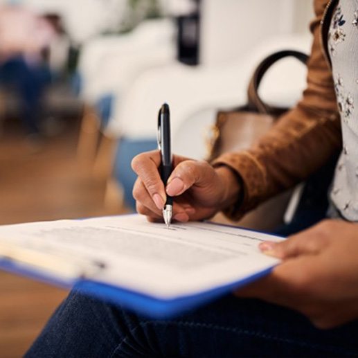 a person filling out a form at a dental office