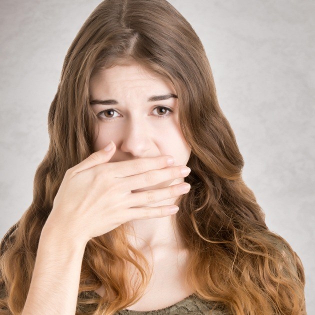 Woman in need of gum disease treatment covering her smile