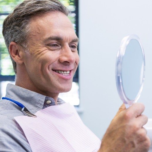 Man looking at smile after dental crown restoration