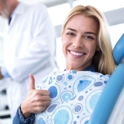 Smiling woman giving thumbs up after dental checkup and teeth cleaning