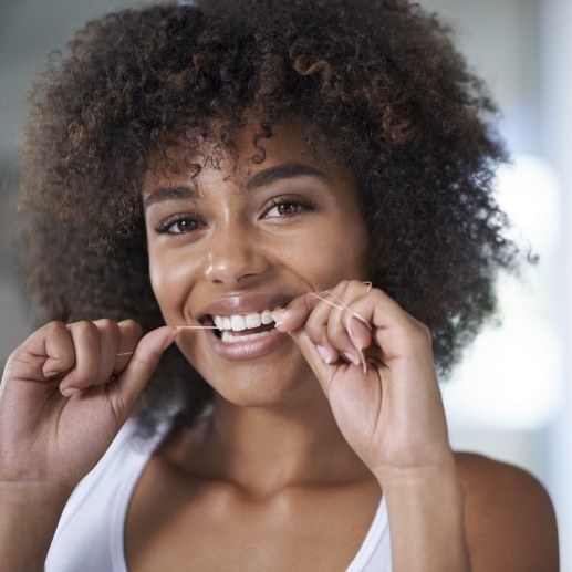 Woman flossing teeth to prevent dental emergencies