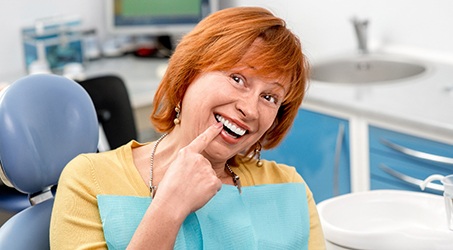 A closeup of a senior woman holding her cheeks while smiling