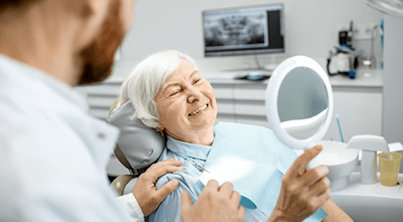 a patient smiling and checking her new dental implants