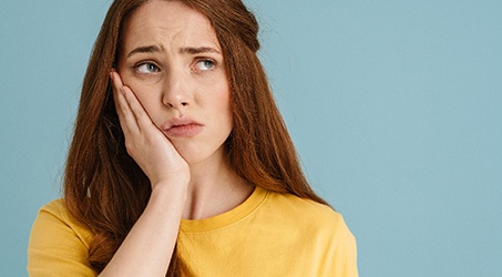 A young woman with a toothache looking aside