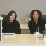 Two friendly dental team members behind reception desk in Springdale dental office