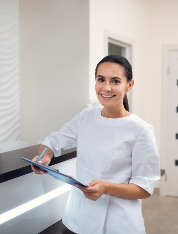 Smiling dental team member holding clipboard