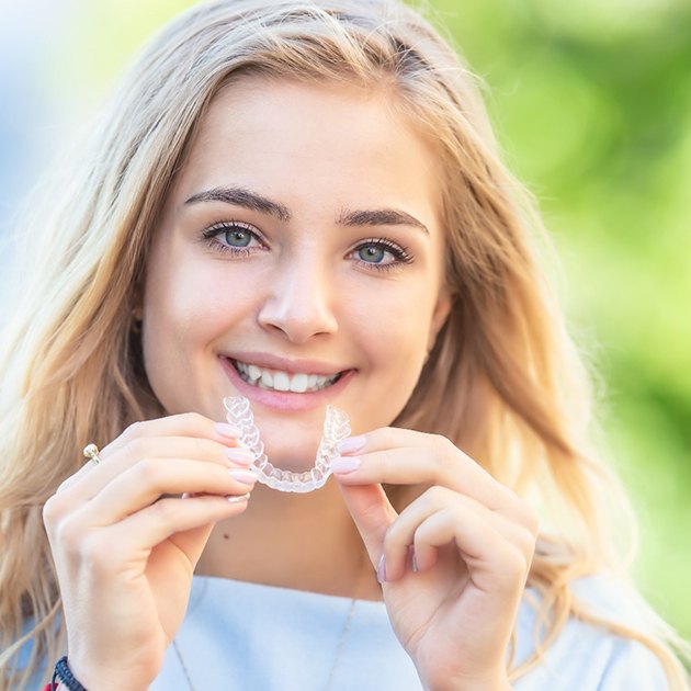 A young woman holding an Invisalign tray