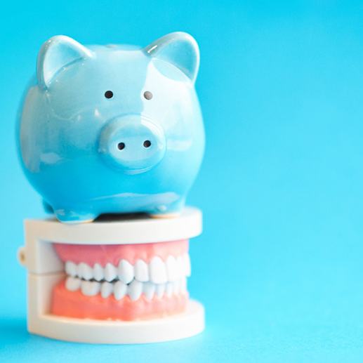 A piggy bank sitting on a jaw model against a blue background