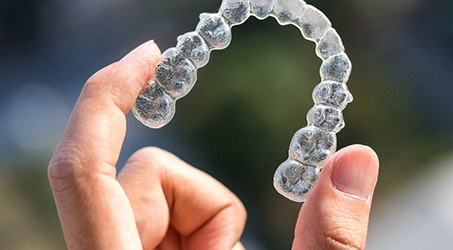 Closeup of patient holding Invisalign aligner outside