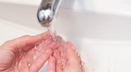 a person cleaning Invisalign aligners with water