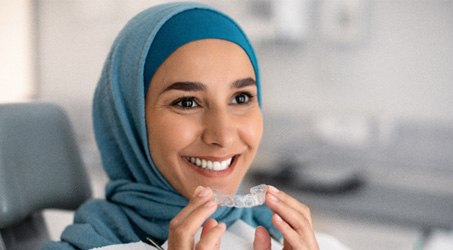 a smiling patient holding Invisalign trays
