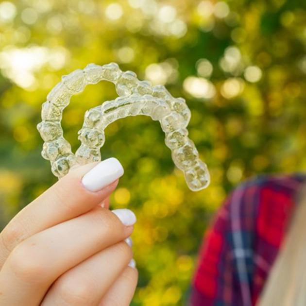 a girl holding her aligners for Invisalign Teen