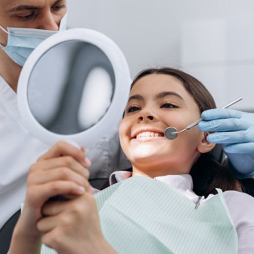 a teen checking her straightened smile with her dentist