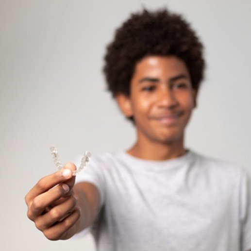 a boy holding his clear trays for Invisalign Teen