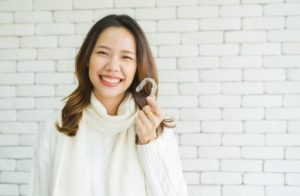 a woman smiling and showing her Invisalign aligner