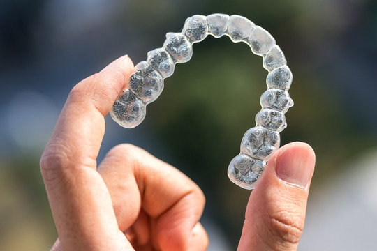 closeup of person holding Invisalign aligner 